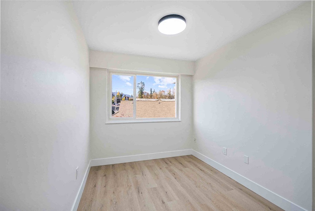 an empty room with a window and wooden floors
