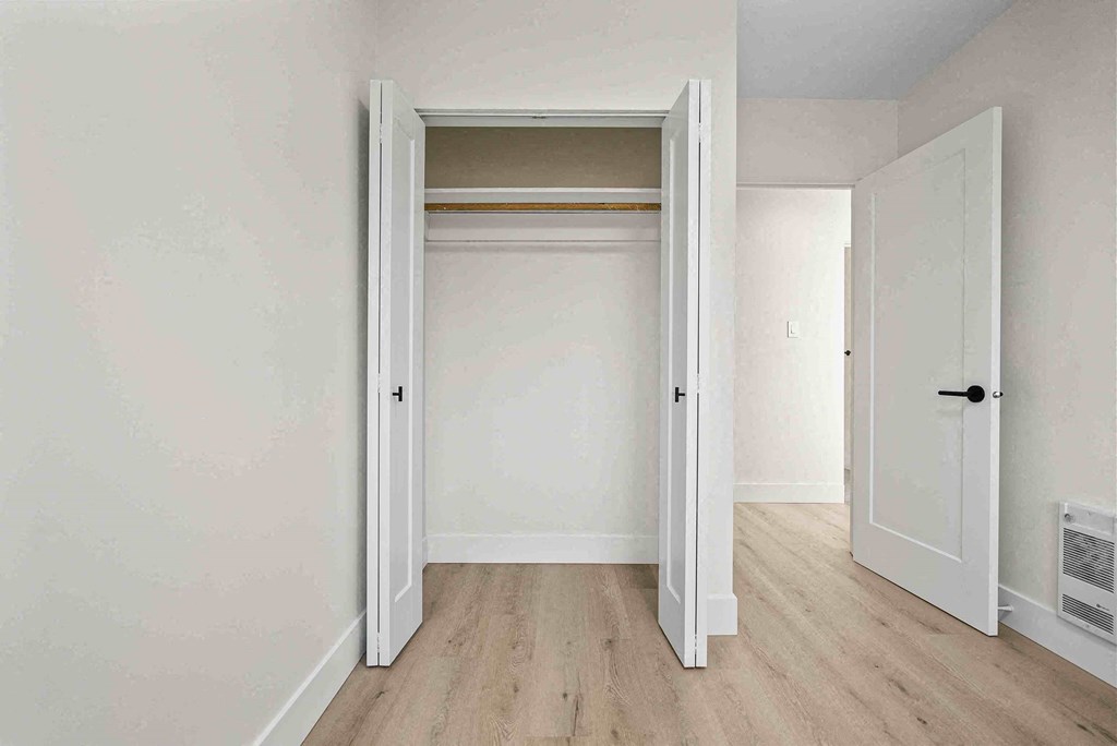 an empty bedroom with a closet with a door open
