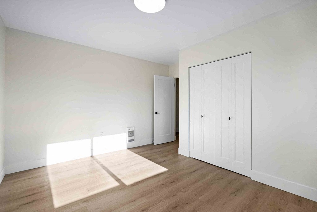 an empty living room with white walls and wooden floors