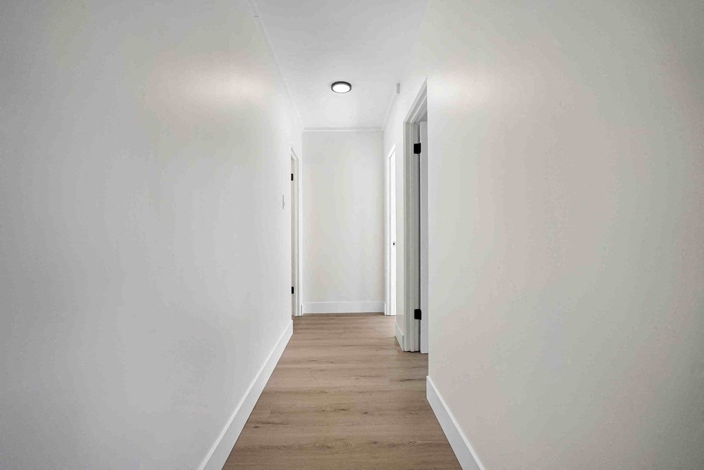 a long white hallway with white walls and wood floors