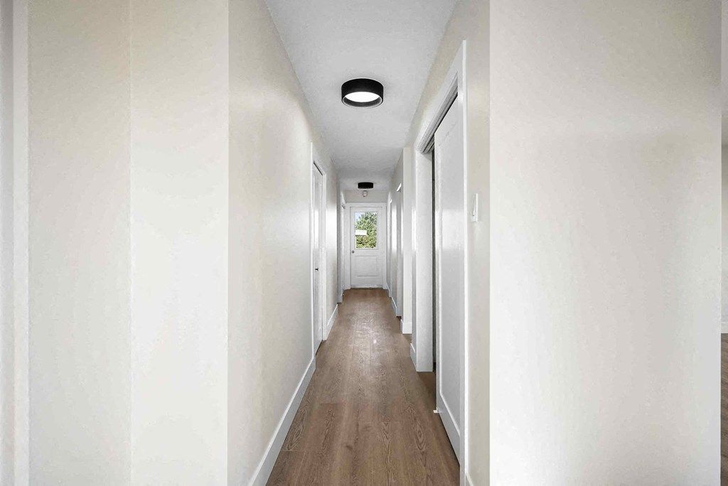a long hallway with white walls and wood floors
