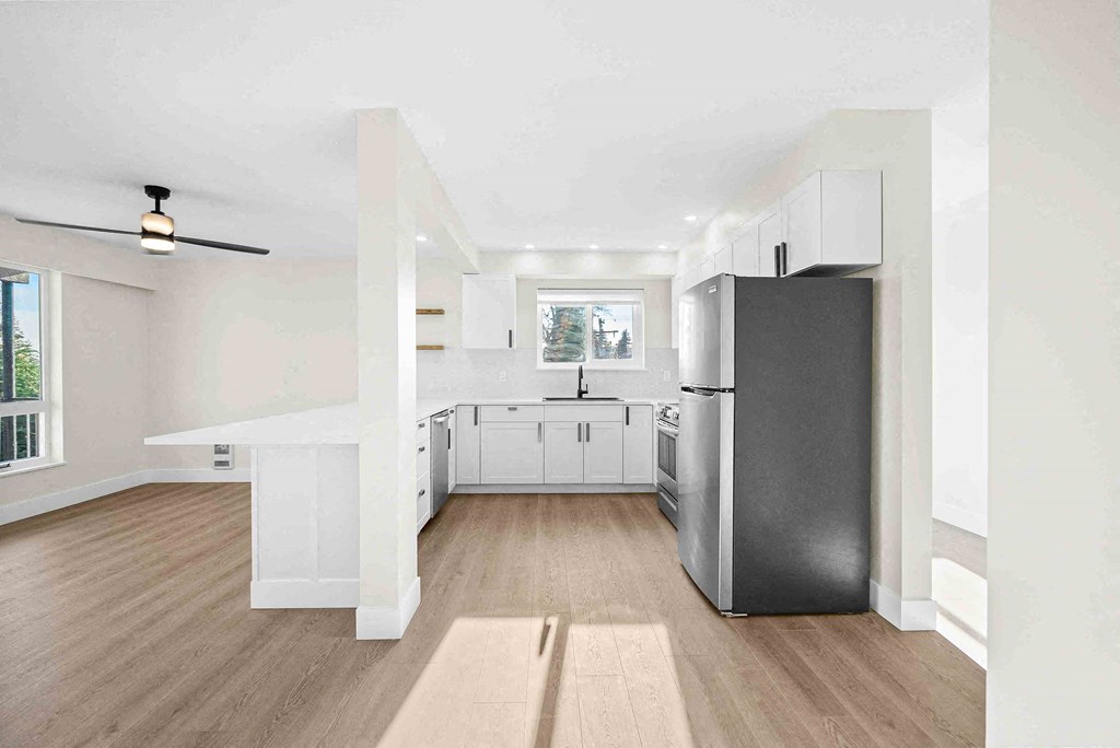 an empty kitchen with a refrigerator and a window