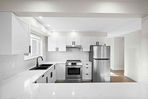 a white kitchen with stainless steel appliances and white counter tops