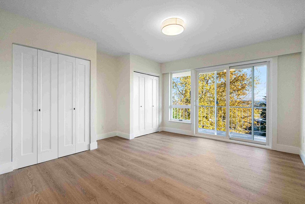 an empty living room with wood floors and a window