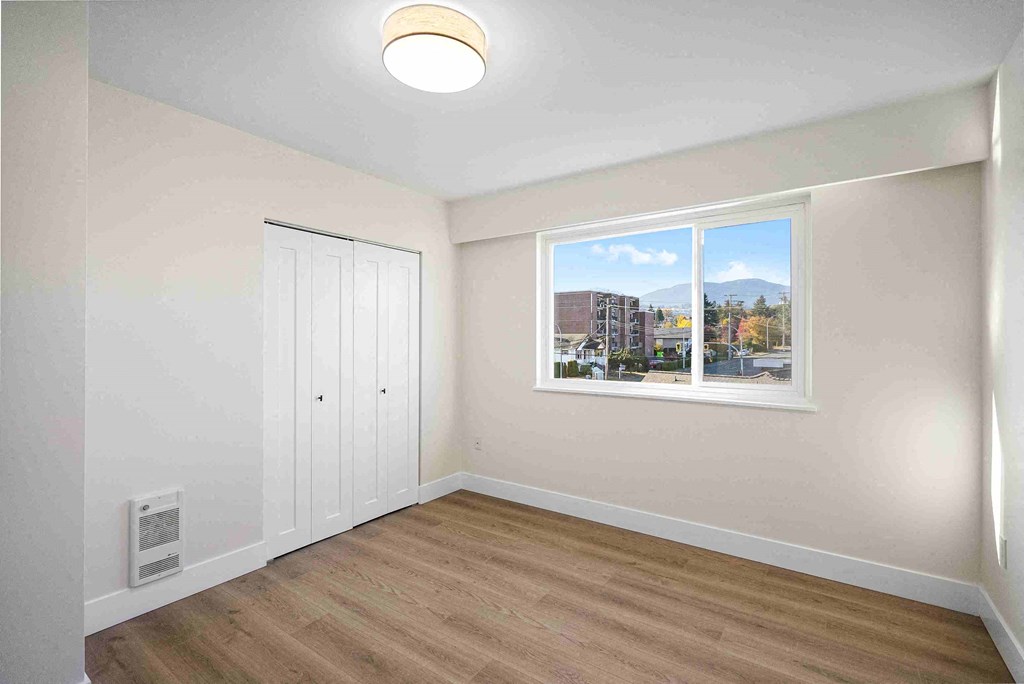 an empty room with a window and a closet