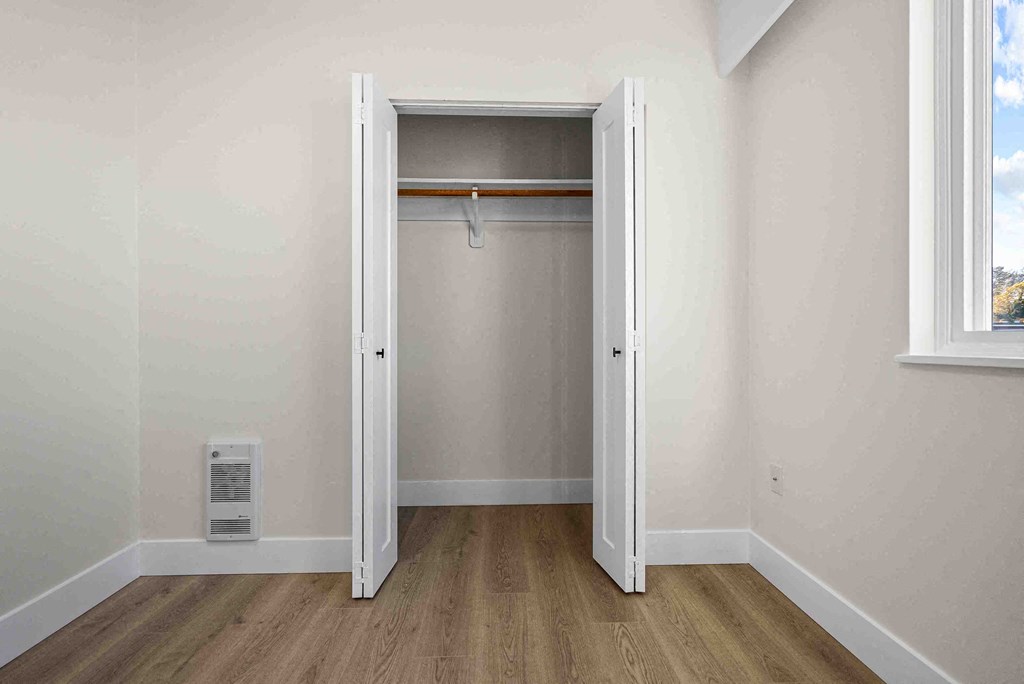 an empty bedroom with a closet with a door open