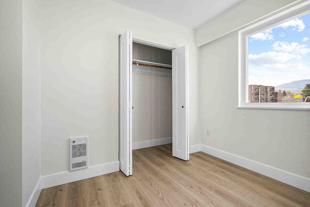 a bedroom with an open closet door and a window
