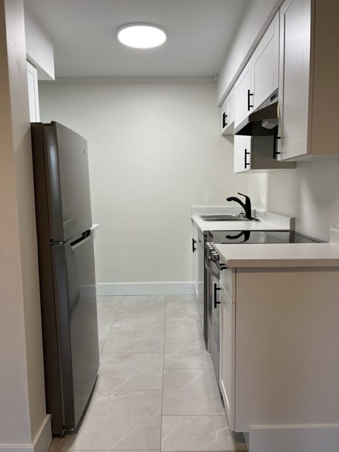 A kitchen with a refrigerator and a sink.
