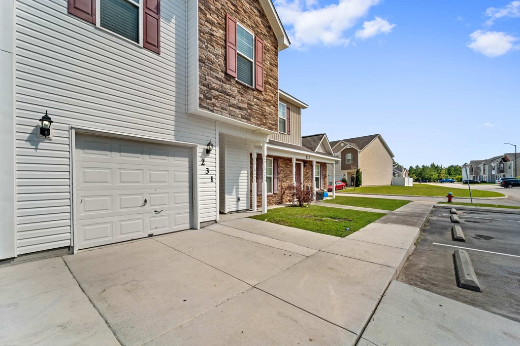 a sidewalk in front of a house with a white garage door