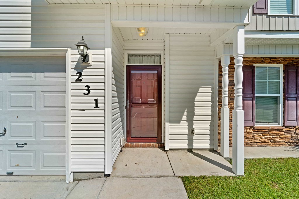 the front of a white house with a red door