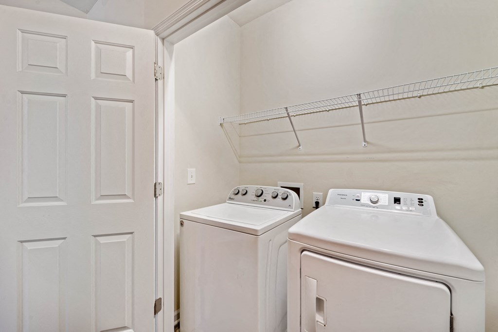 a laundry room with two white appliances and a white door