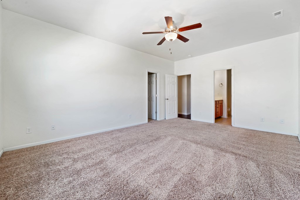 an empty living room with a ceiling fan