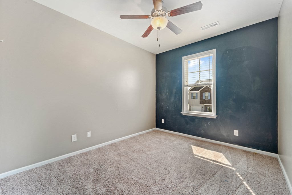 an empty room with a ceiling fan and a window