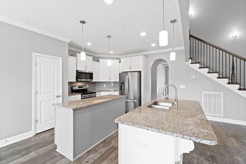an open kitchen with a marble counter top and a sink