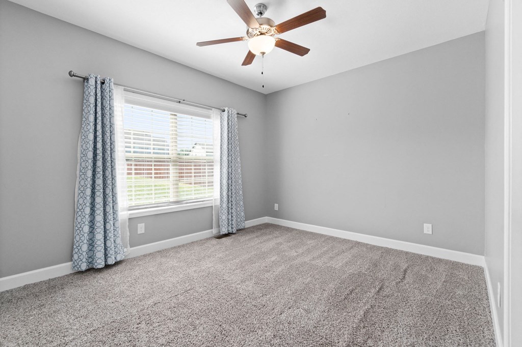 an empty living room with a ceiling fan and a window