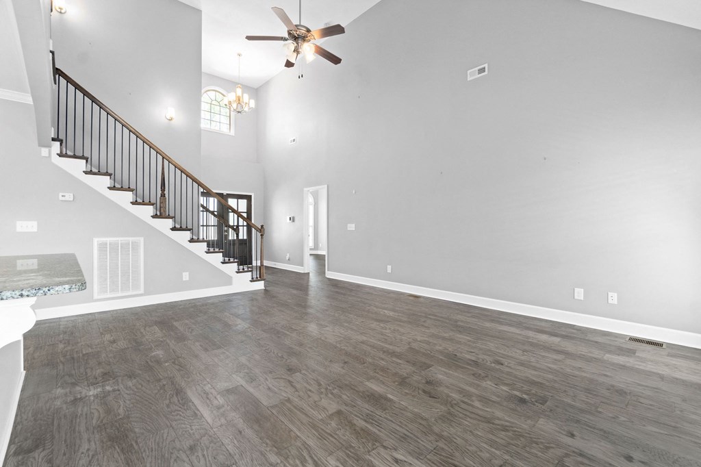the living room and entryway of a house with white walls and a ceiling fan