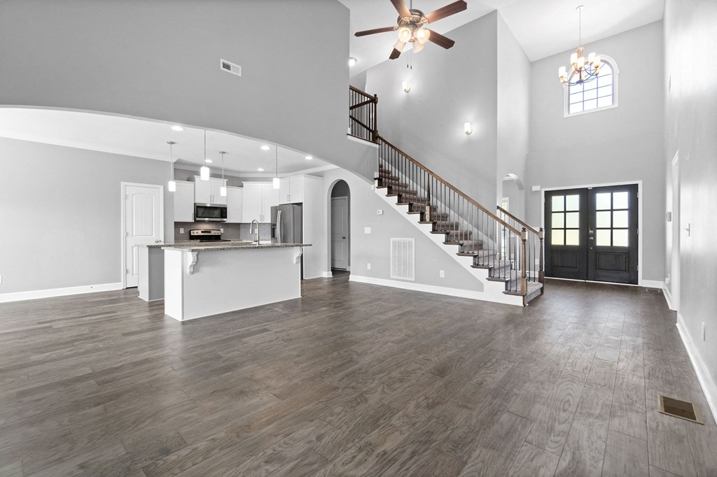 an empty living room with a staircase and a kitchen
