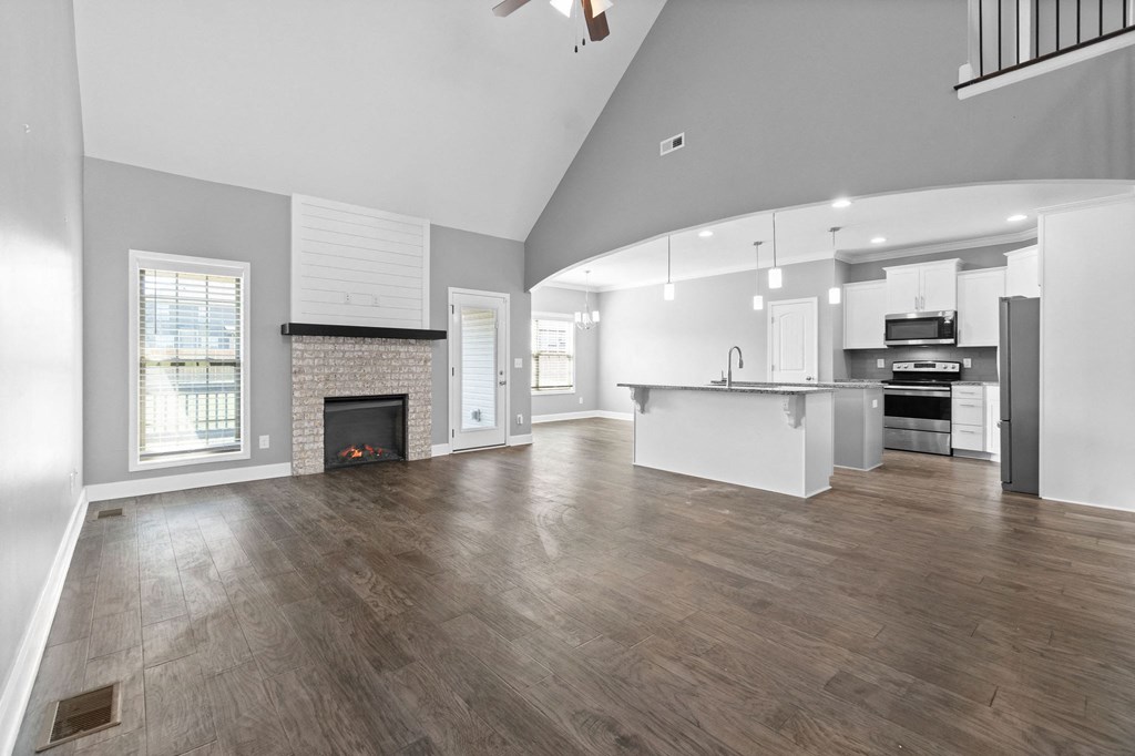 an empty living room with a fireplace and a kitchen
