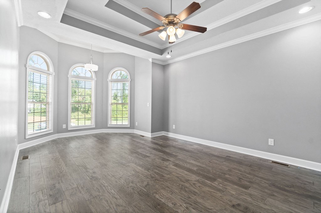 an empty living room with a ceiling fan and windows
