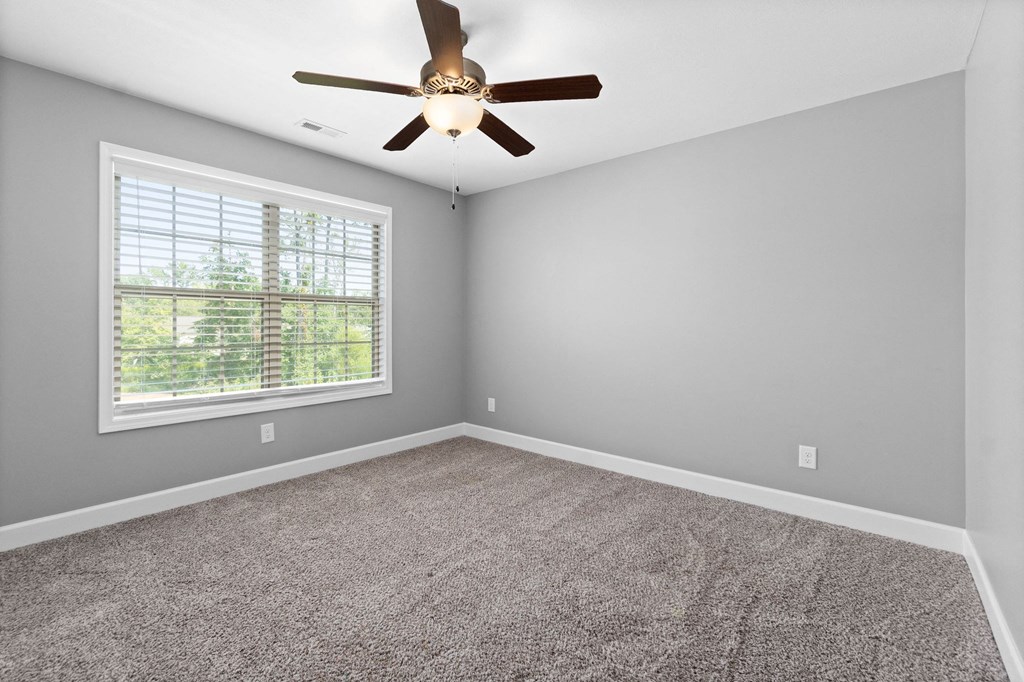 an empty bedroom with a ceiling fan and a window