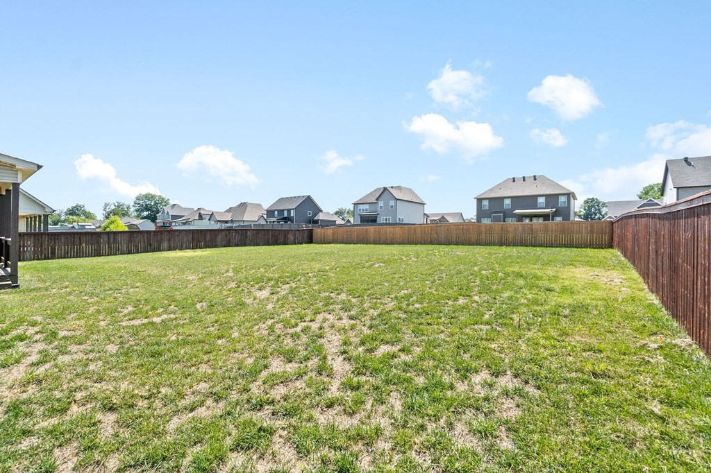 a backyard with a fence and houses in the background