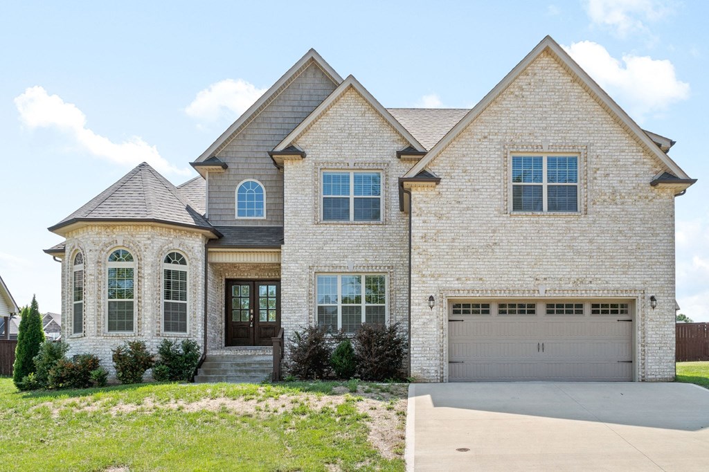 a home with a garage door and a brick house