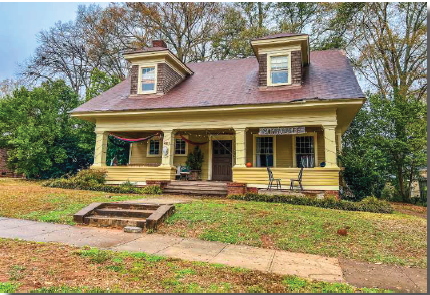 a yellow house with a porch and a sidewalk