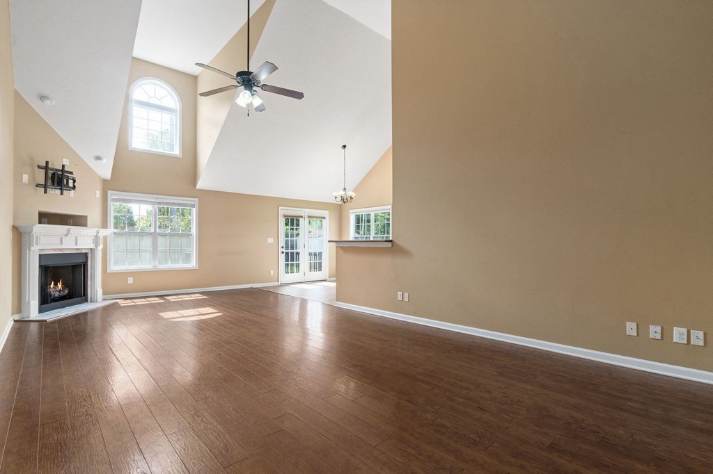 an empty living room with a ceiling fan and a fireplace
