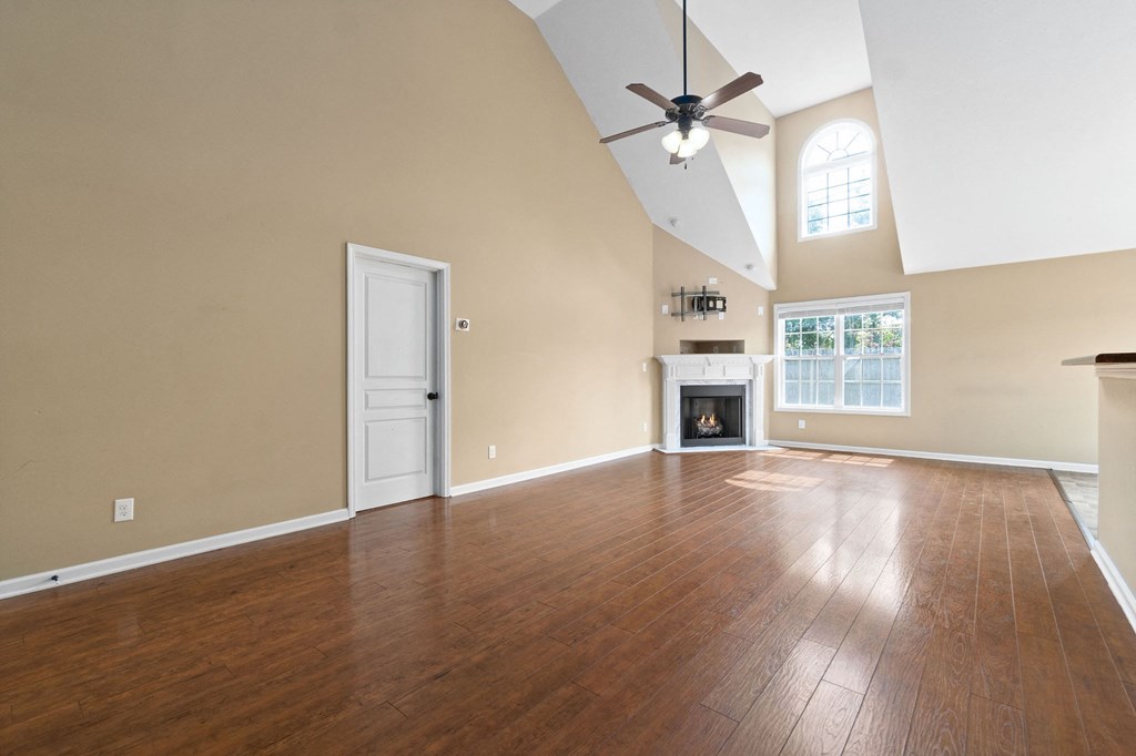 an empty living room with a ceiling fan and a fireplace