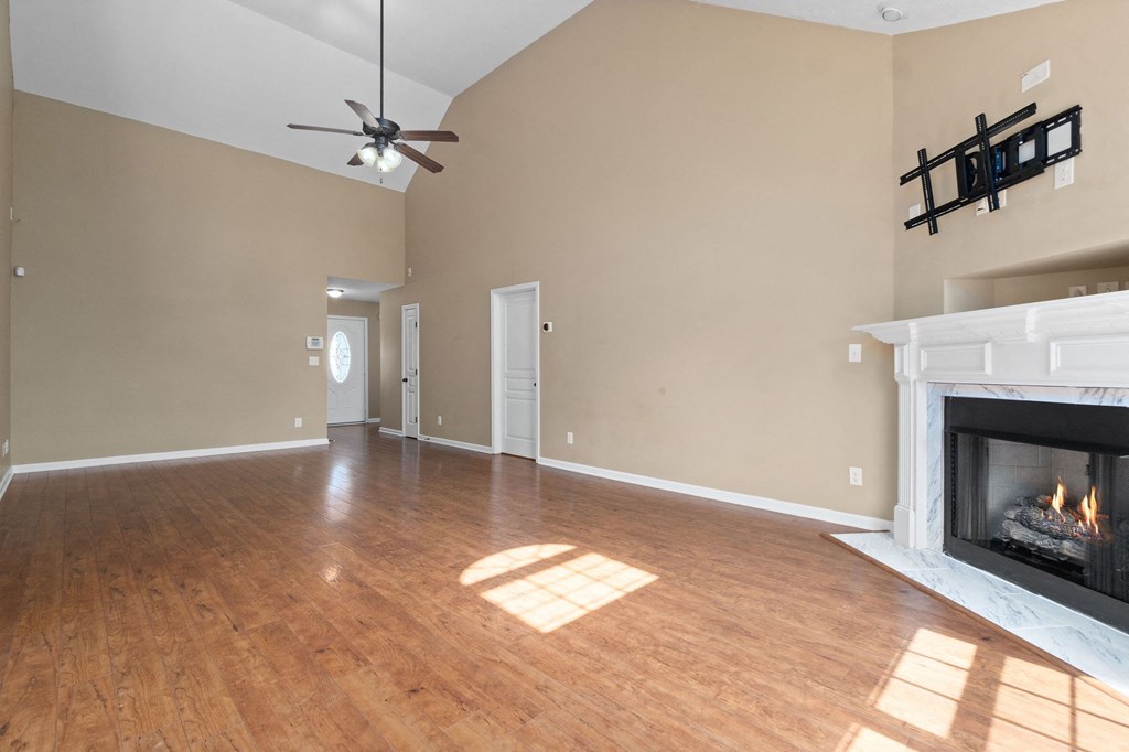 an empty living room with a fireplace and a ceiling fan