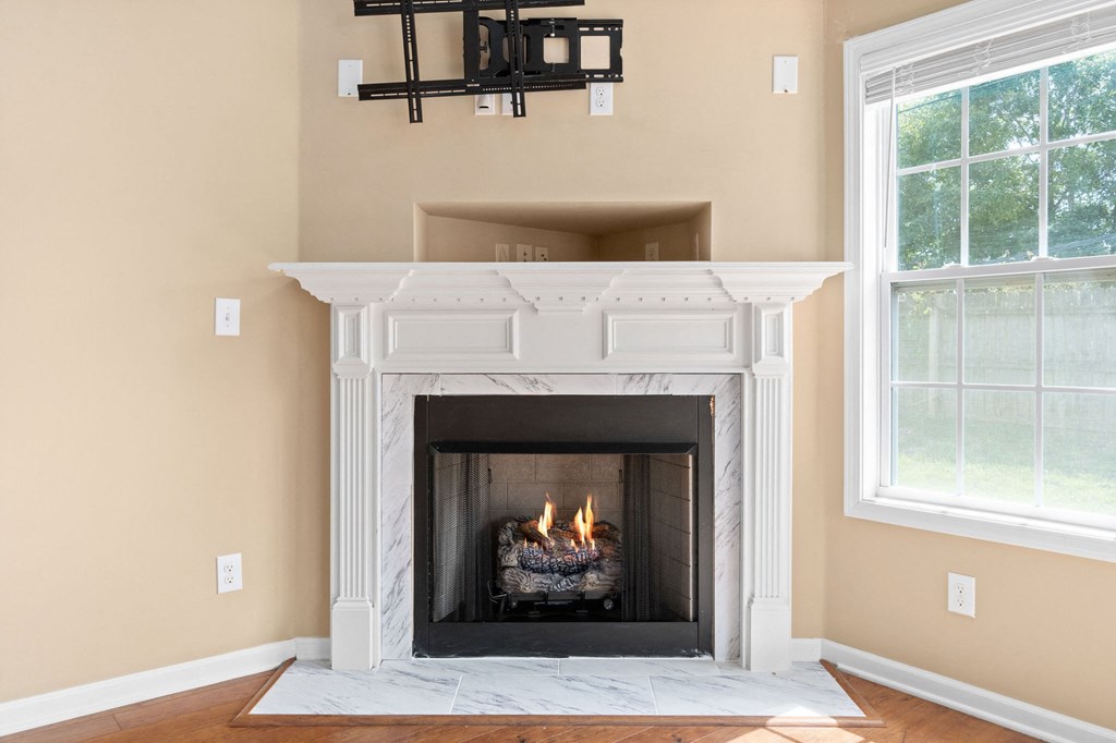 a fireplace with a white mantle in a living room with two windows