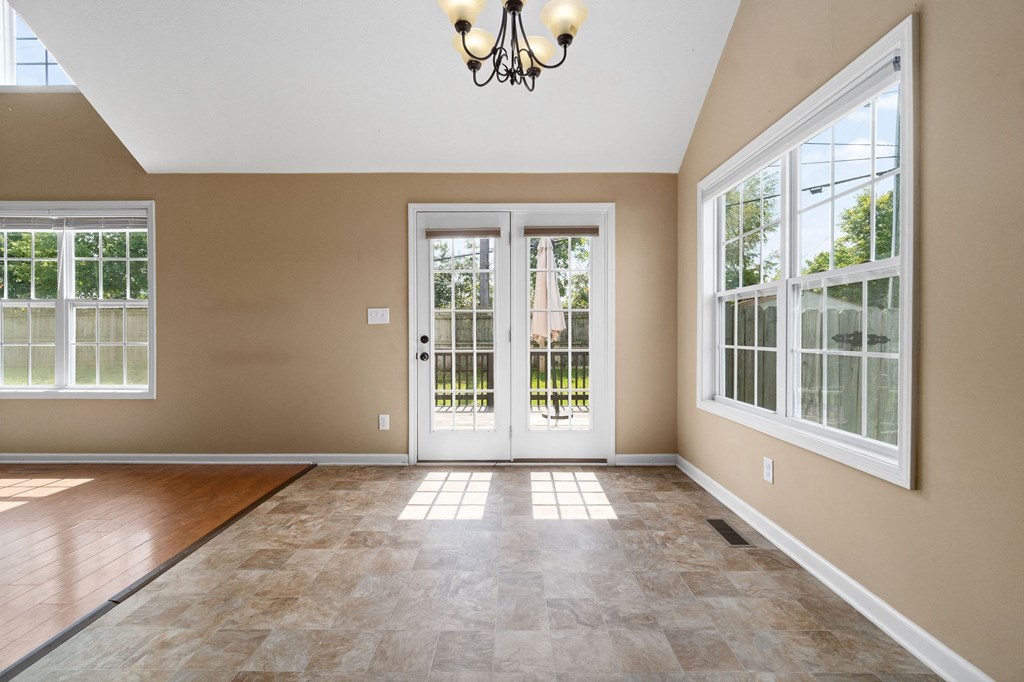 an empty living room with doors and a chandelier
