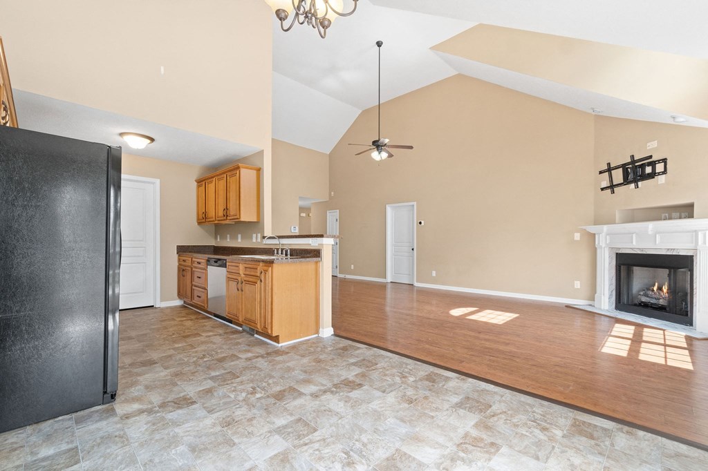 an empty living room with a fireplace and a kitchen
