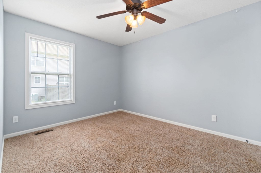 an empty room with a ceiling fan and a window