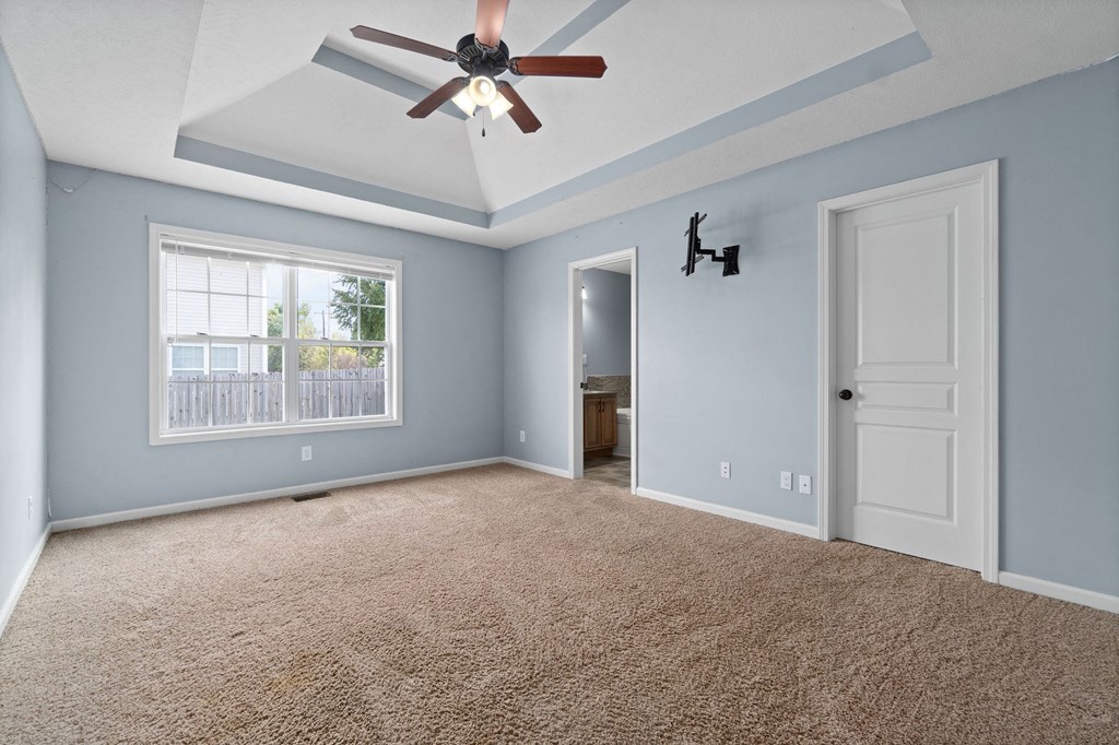an empty living room with a ceiling fan and a window