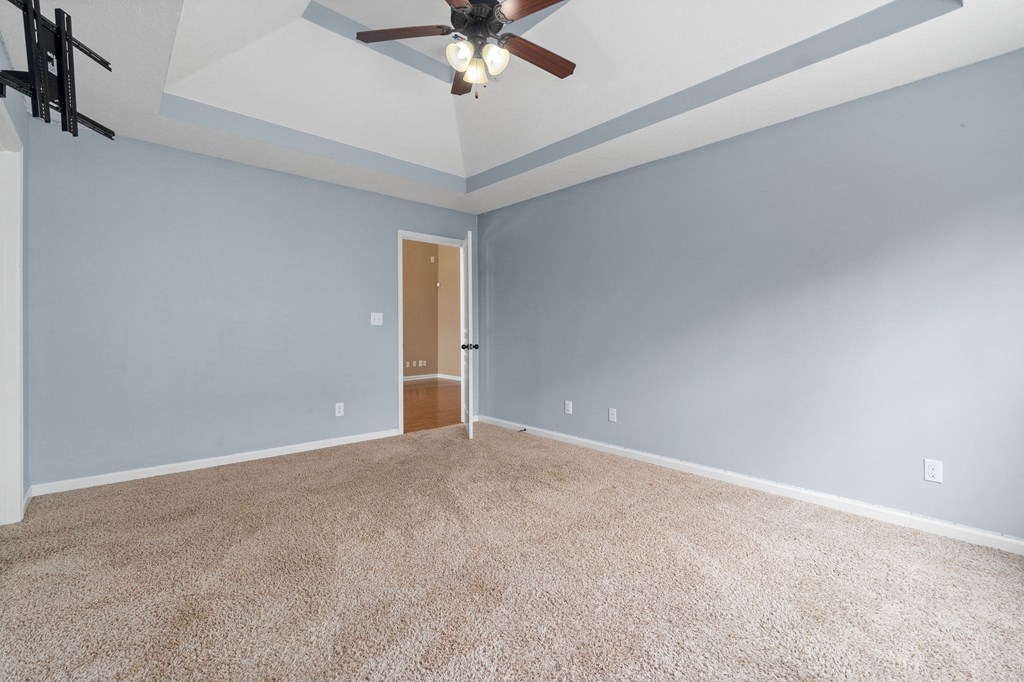 an empty living room with blue walls and a ceiling fan