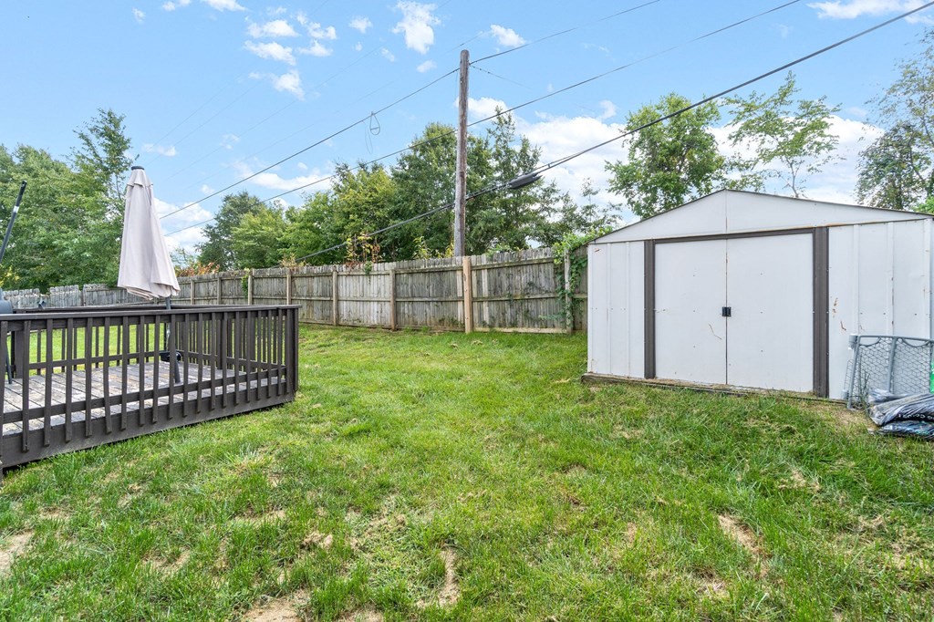 a backyard with a fence and a shed and an umbrella