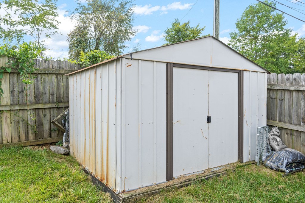 a small white shed in a backyard with a fence
