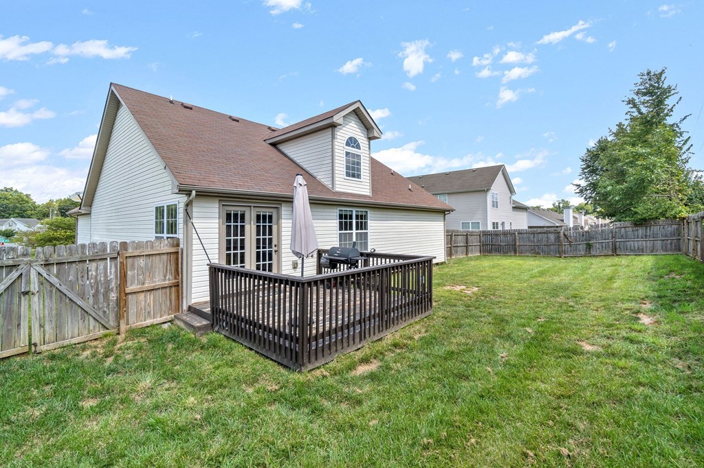 the backyard of a house with a fence and a patio with an umbrella
