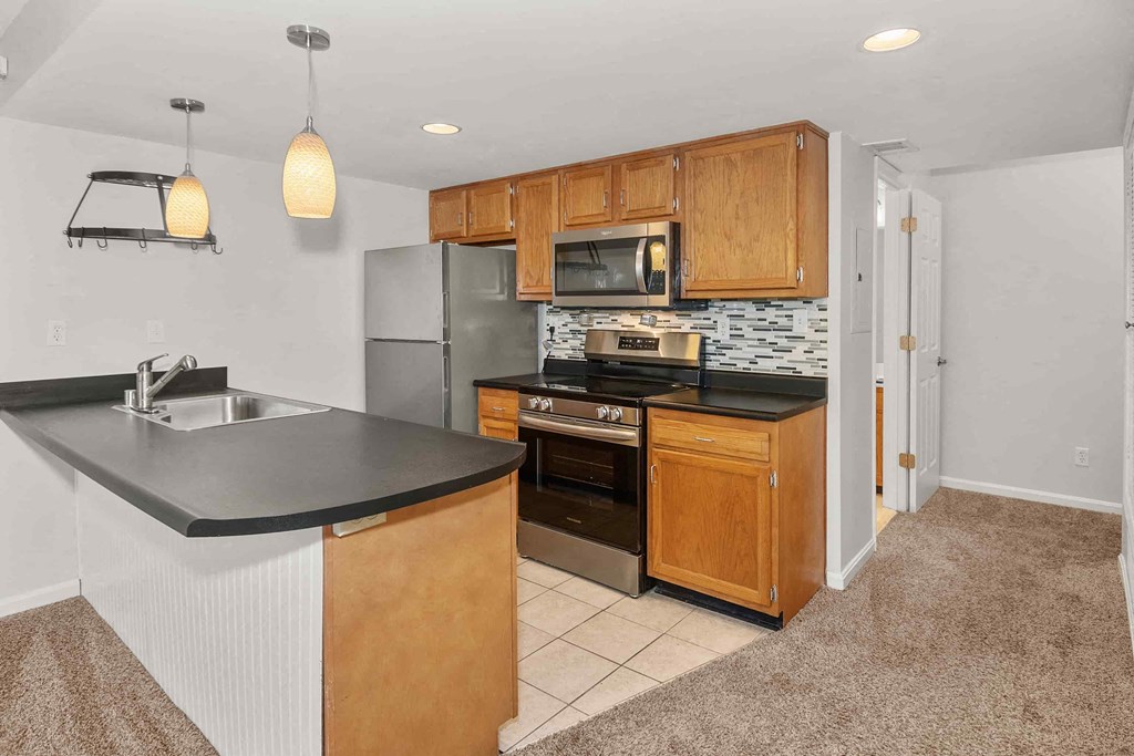 A kitchen with wooden cabinets and a black countertop.