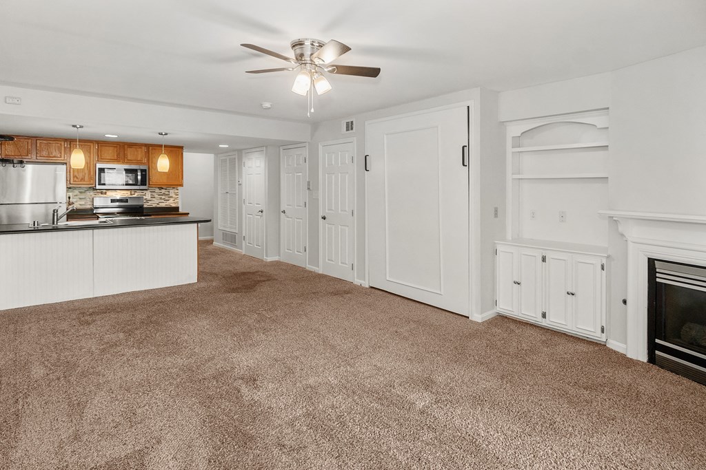 A spacious kitchen and living room with white cabinetry and a fireplace.