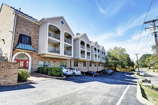 A sunny day at the Hearth Apartments with cars parked in the lot.