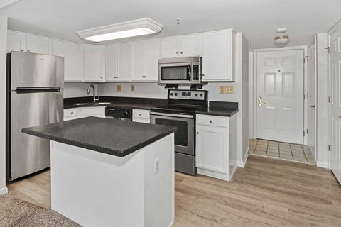 A kitchen with white cabinets and a black countertop.