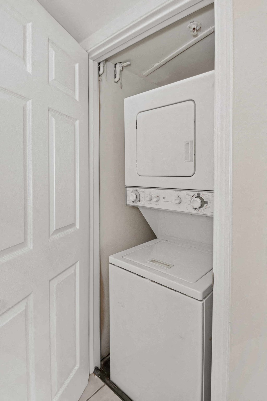 A white dryer is in a small closet.