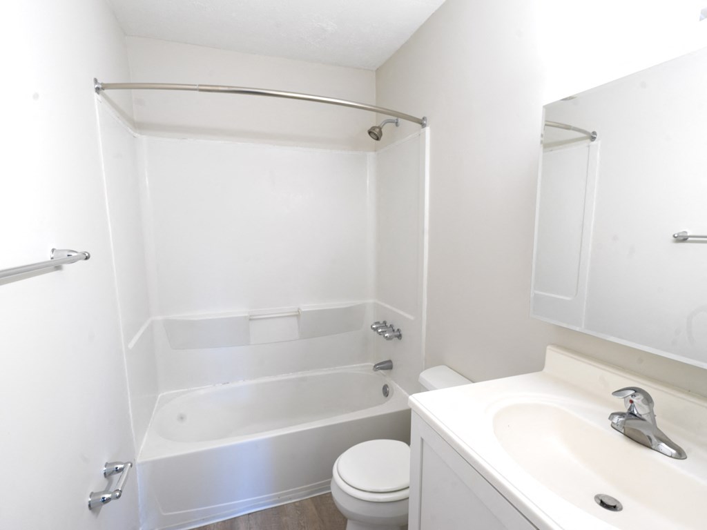A white bathroom with a toilet, sink, and bathtub.