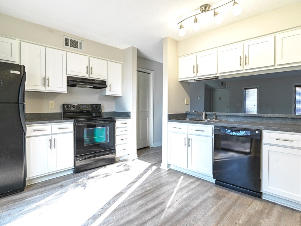 A kitchen with black appliances and white cabinets.