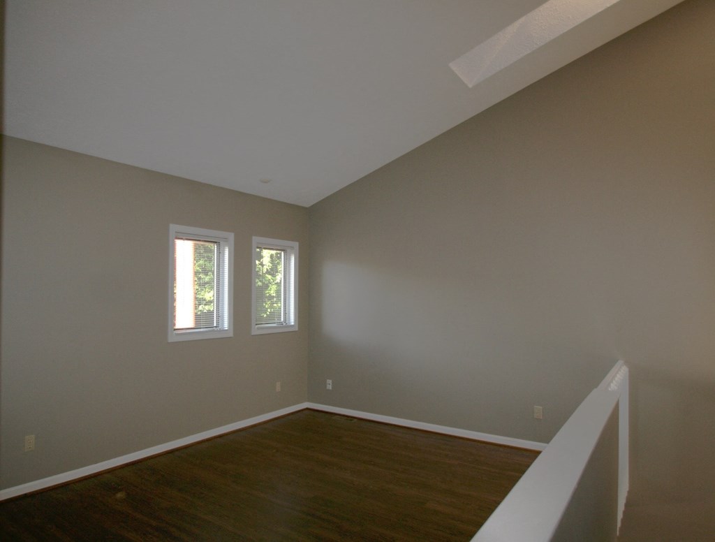 A room with wooden floors and two windows.