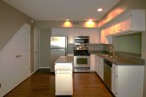 A kitchen with white cabinets and a wooden floor.