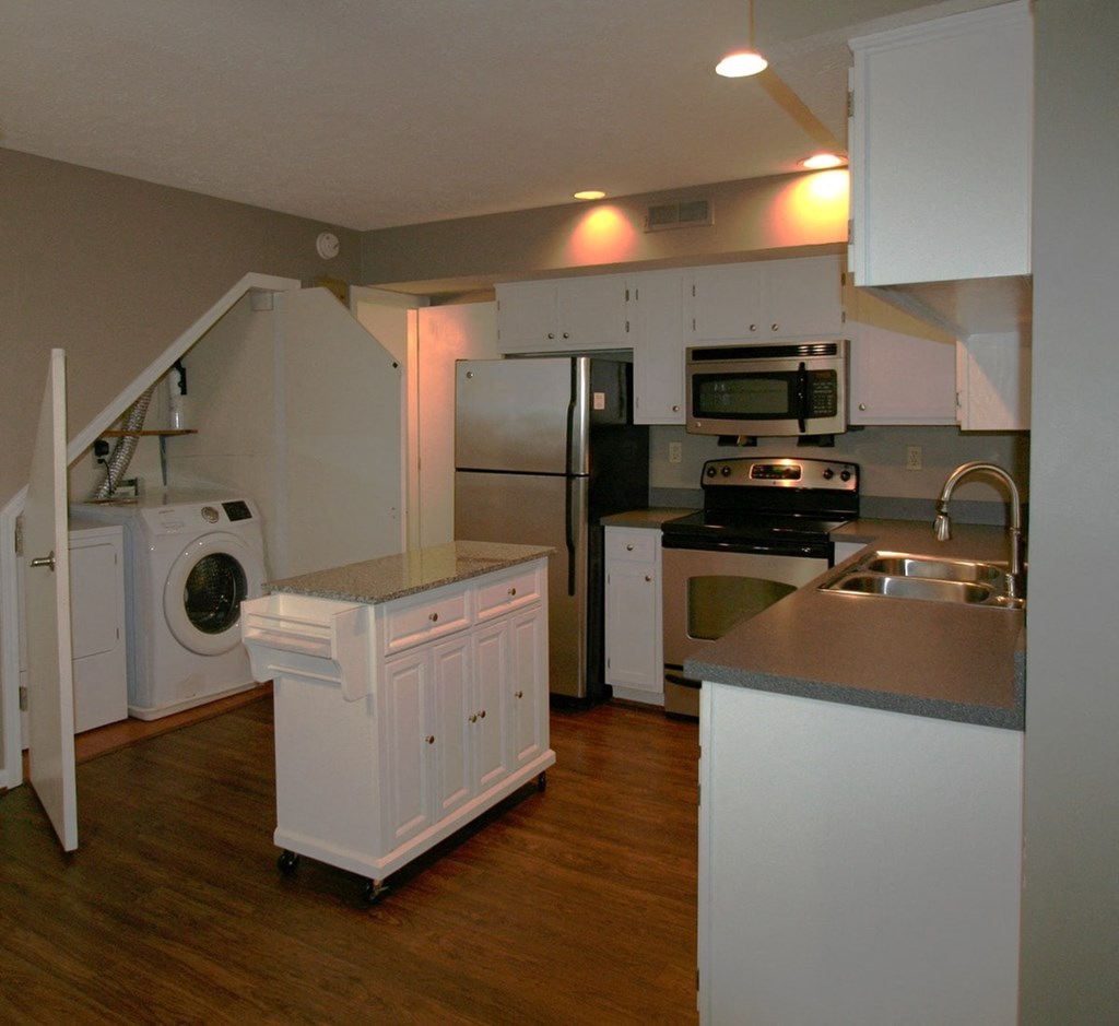 A kitchen with white appliances and wooden floors.