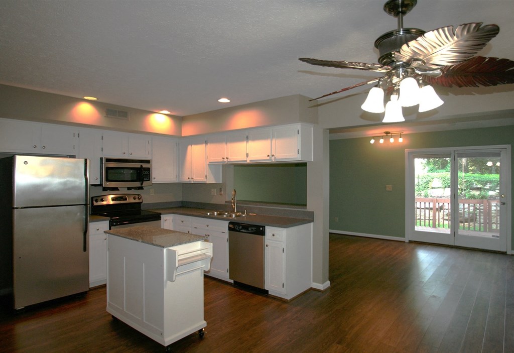 A kitchen with white appliances and wooden floors.